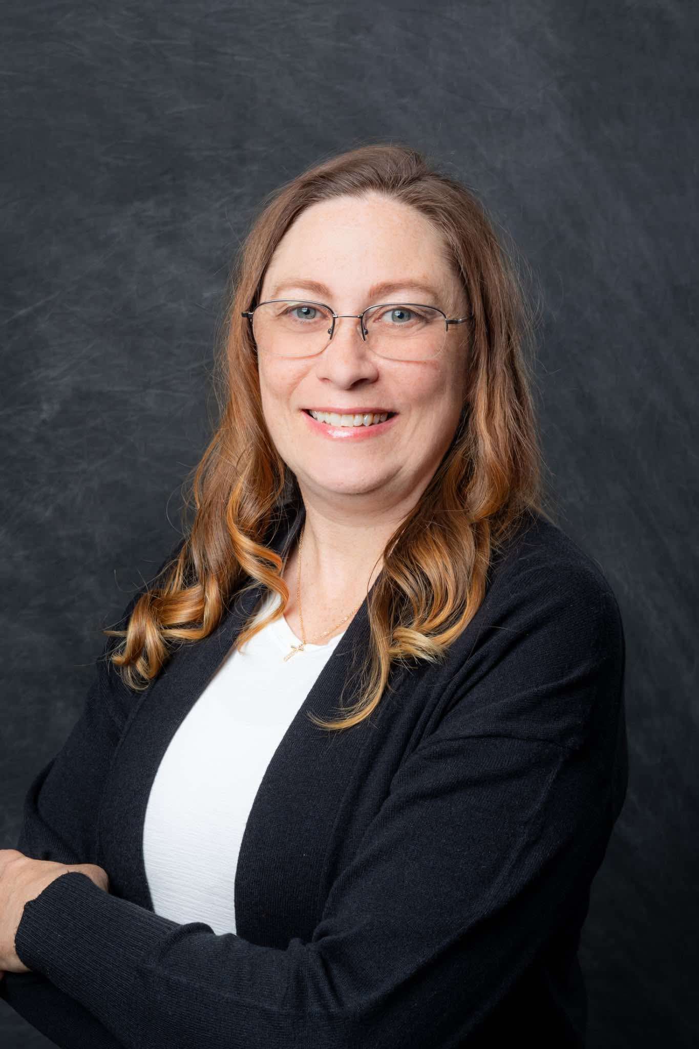 Professional headshot of smiling woman with glasses